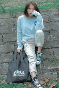 Full length of young woman sitting on wall