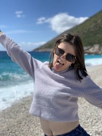 Woman wearing sunglasses standing at beach youth at 2021. girl power 