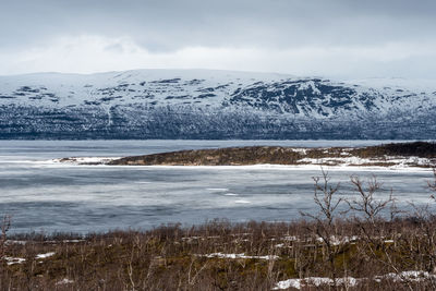 Scenic view of sea by snowcapped mountain against sky