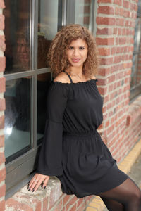 Portrait of young woman sitting on window sill