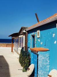 View of building by sea against clear blue sky