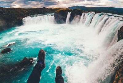 Low section of person against waterfall