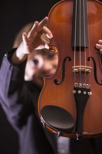 Boy playing violin against black background