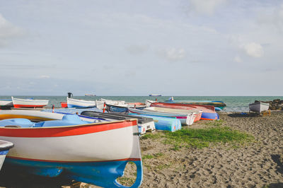 Boats moored on the beach against the sky