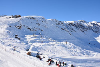 People on snowcapped mountain against blue sky