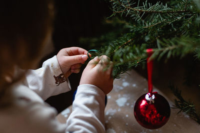 Children hands decorating christmas tree at home