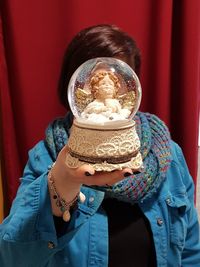 Close-up of woman covering face with snow globe