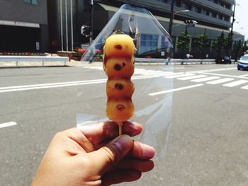 Close-up of man holding ice cream on road