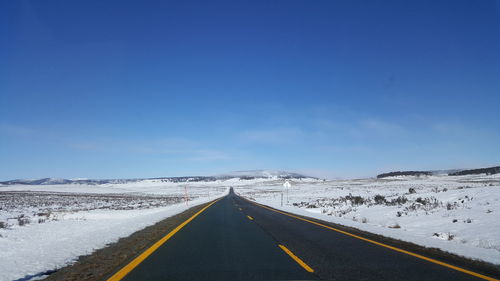 Empty road against blue sky during winter