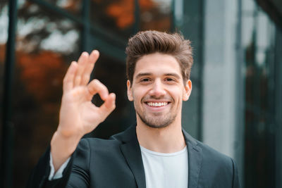 Portrait of smiling young businessman showing ok sign 