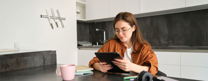 Side view of young woman using mobile phone at home