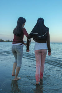 Rear view of women on beach against sky