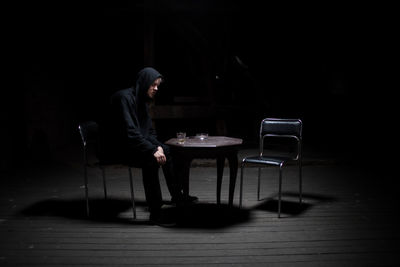 Side view of young man sitting on table at home