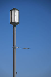 Low angle view of security camera against clear blue sky