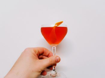 Midsection of woman holding drink against white background