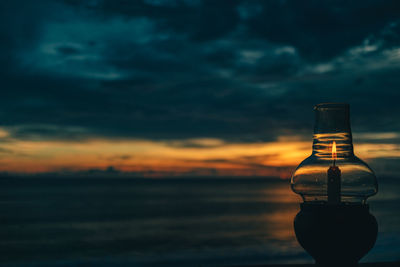 Wine bottles on beach against sky during sunset