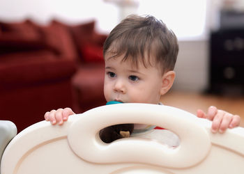 Cute boy with a pacifier behind a safety separator