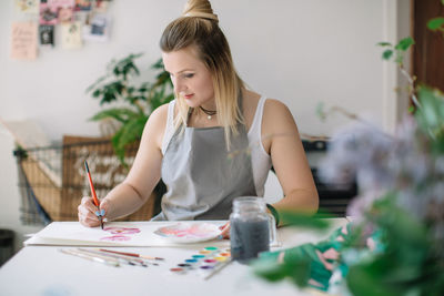 Woman painting in book at home