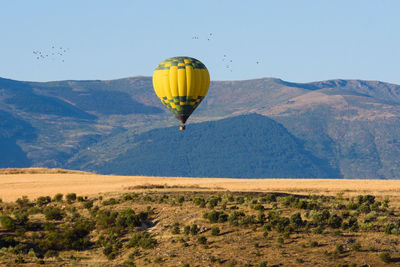Hot air balloon flying over mountain against sky