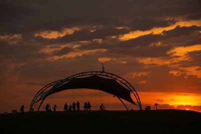 Silhouette people on land against sky during sunset