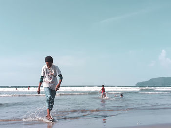 Men standing on beach against sky