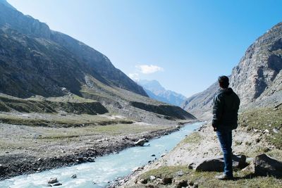 Man standing by river against mountain range