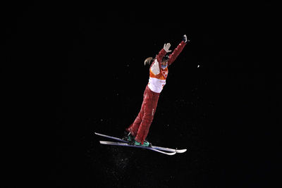 Low angle view of woman dancing against black background