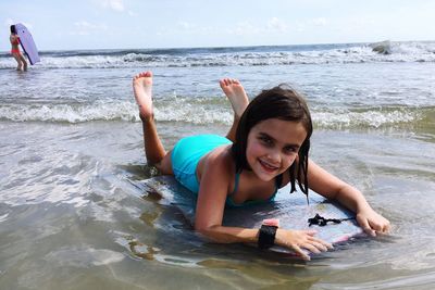 Portrait of smiling young woman on beach against sky