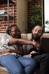 Friends using laptop while sitting at home