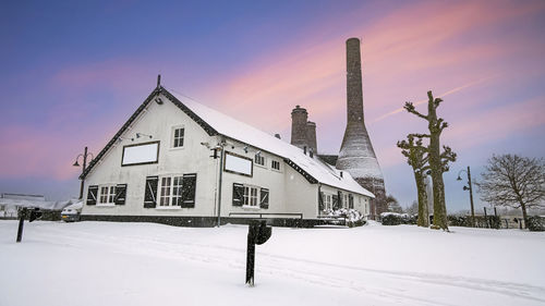 House on snow covered field against sky