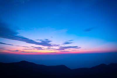 Scenic view of silhouette mountains against blue sky at sunset