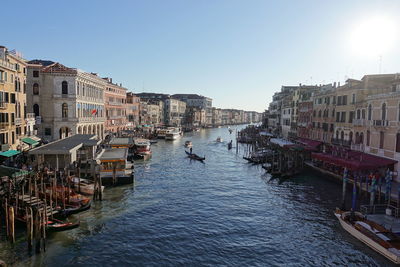 Boats moored in canal in city against clear sky