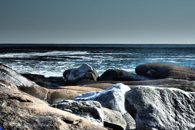 Rocks on beach against clear sky