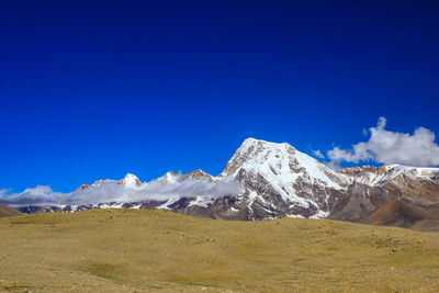 Scenic view of snowcapped mountains against blue sky