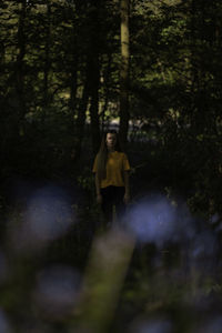 Woman standing amidst trees in forest