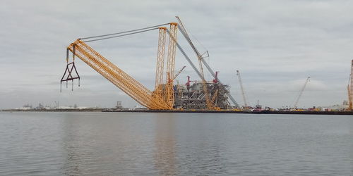 Cranes at commercial dock against sky