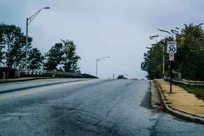 Road sign by street against sky