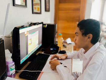 Midsection of man using mobile phone while sitting on table