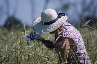 Side view of woman with flowers on field