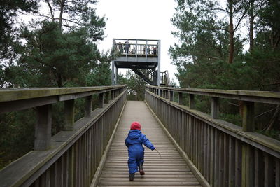 Rear view of child running on wooden bridge at salcey forest