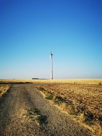 Wind turbines on field against clear blue sky