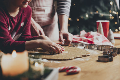 Mom and daughter make gingerbread cookies, cut out different shapes using cutting mold at kitchen