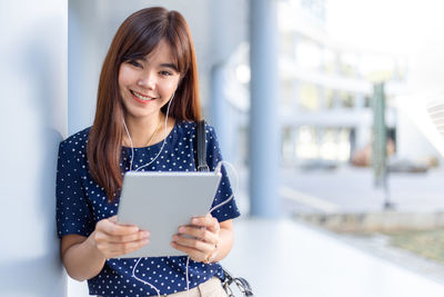 Portrait of a smiling young woman using smart phone