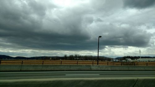 View of field against cloudy sky