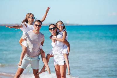 Full length of friends enjoying at beach against sky