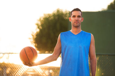 Young man with ball in background against sky