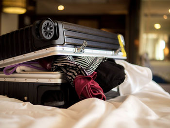 Close-up of suitcase with clothes on bed at home