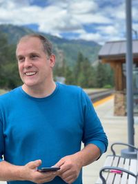 Smiling man looking away while standing against mountains