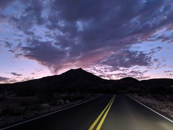 Road leading towards mountains against sky