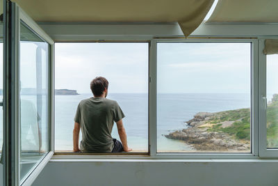 Rear view of woman looking through window